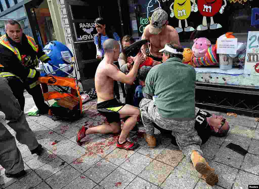 Bystanders tend to a man injured in the explosions.