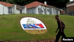 A man walks past a floral display announcing the 5th BRICS summit in Durban.