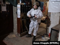 Iryna, a Ukrainian soldier, readies her weapon in an operating base before hiking to a frontline position.