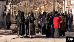 Afghan female students are stopped by Taliban security personnel stand next to a university in Kabul on December 21. 