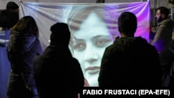 Protesters looks at an image of Mahsa Amini, whose death in police custody in September has sparked months of protests, during a candlelight vigil in front of Iranian Embassy in Rome.