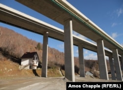 A house sits under a raised section of the new Montenegrin highway, near Matesevo.