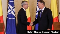 NATO Secretary-General Jens Stoltenberg (left) shakes hands with Romanian President Klaus Iohannis in Bucharest. (file photo)