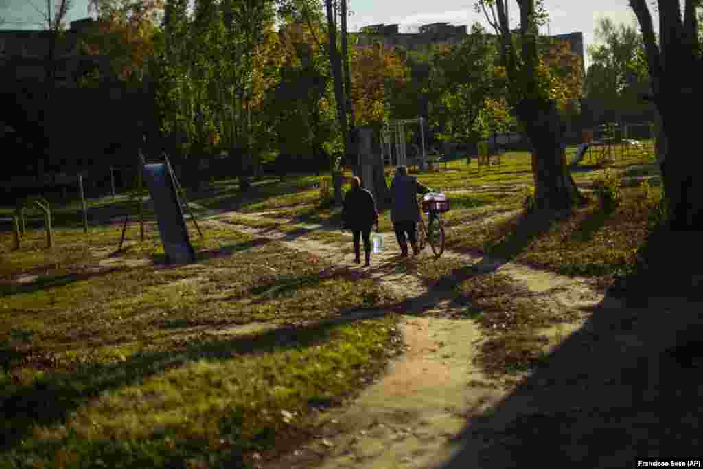 Locals in Kivsharivk carry plastic bottles of water after filling them up at a local well. Authorities in the Ukrainian-controlled areas have urged all remaining residents to evacuate, and&nbsp;warned that gas and water services in many areas&nbsp;will likely not be restored by winter.