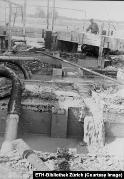 A worker and pools of drilling mud in Aricesti