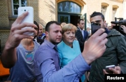 Refugees from Syria and Iraq take selfies with German Chancellor Angela Merkel outside a refugee camp near the Federal Office for Migration and Refugees in Berlin in September.