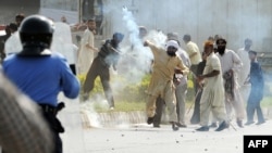 A demonstrator throws a tear gas shell toward Pakistani riot police during a protest against the film "Innocence of Muslims" in Islamabad.