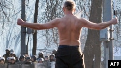 A shirtless man waves a Ukrainian flag during clashes between the opposition and police in downtown Kyiv on January 20.