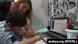 Twelve-year-old Roman Kaimashnikov and his mother, Tatiana Kaymashnikova, go over an online lesson together.