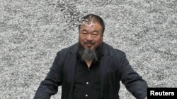 Chinese artist Ai Weiwei throws porcelain sunflower seeds into the air as he poses with his "Sunflower Seeds" installation in the Turbine Hall at the Tate Modern art gallery in London in October 2010.