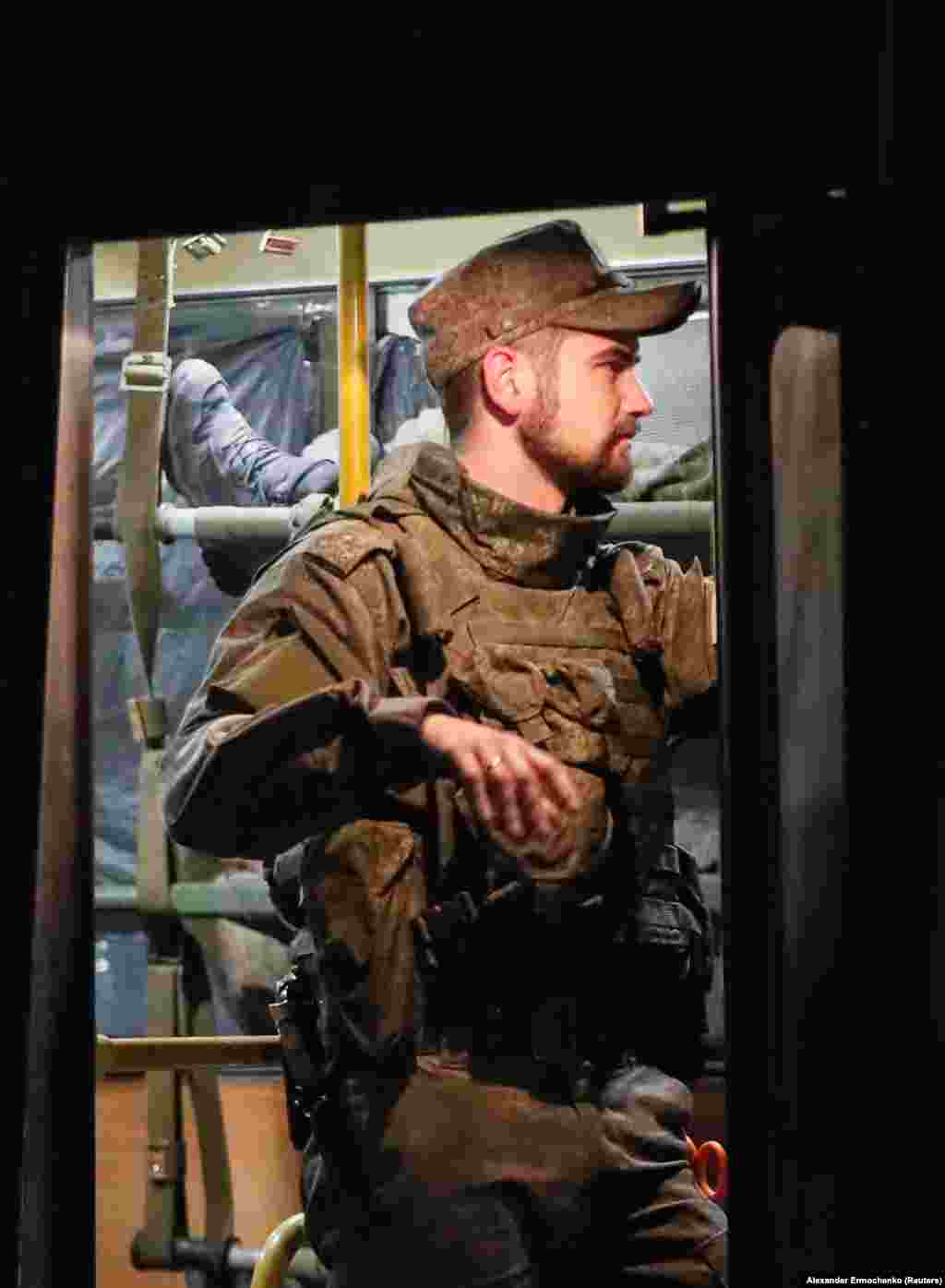 A separatist fighter stands guard over a bus&nbsp;carrying wounded Ukrainian soldiers from Mariupol.&nbsp;