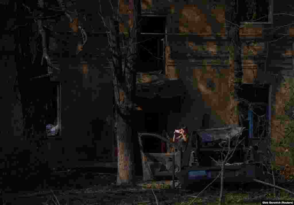 A woman takes a photo of the devastation caused by a missile strike in Kramatorsk.