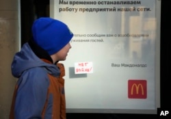 A boy walks past a "No War!" sign stuck to the window of a McDonald's with a restaurant closing notice in St. Petersburg on March 15.