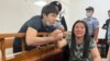 Bayan Shyrynbekova (right), whose husband Alibek Imanbekov (left) was sentenced to six years in prison on a charge of stealing firearms from a store in Almaty during the unrest, says he had to sign a written confession after he was "beaten and tortured" by investigators. 