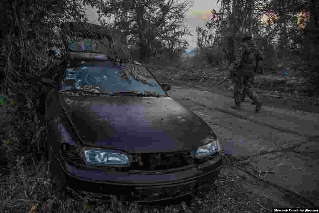 A Ukrainian soldier patrols near a damaged car in Syevyerodonetsk.&nbsp;