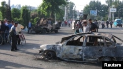 Residents pass burnt-out cars after the unrest in the eastern Uzbek town of Andijon on May 13, 2005.