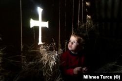 Turcu's young son looking at a cross carved into the attic of an old house in Maramures County in 2022. The boy said "Look Dad, there’s God here," when he saw the cutout.