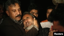 A man is comforted by his family as he mourns his brother, who was killed in the blast.