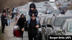 Refugees walk past vehicles lining up to cross the border from Ukraine into Moldova near Mayaky-Udobne, Ukraine, on February 26.