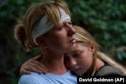 Nelia Fedorova (left), injured in a Russian rocket attack, is embraced by her daughter, Yelyzaveta Gavenko, 11, as they visit the home of a neighbor in Kramatorsk who was killed in the same barrage on August 12.