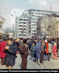 Crowds gather near a badly damaged apartment block in central Bucharest.