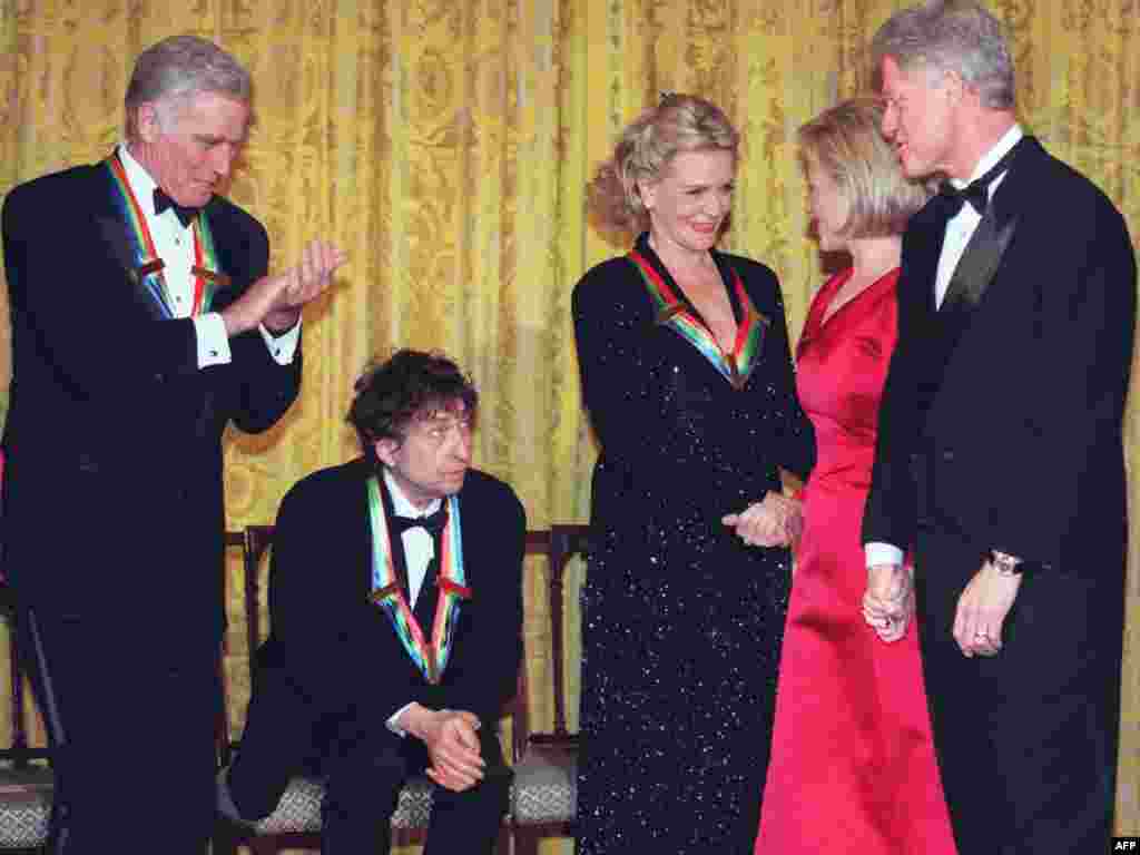 Dylan (seated) and fellow Kennedy Center honorees Charlton Heston (left) and Lauren Bacall in December 1997, with U.S. President Bill Clinton and first lady Hillary Clinton.