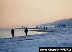 People walk along the snow-covered coastline of the Sea of Azov in Mariupol on February 6.