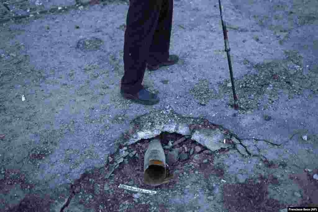 A local man walks past a Russian rocket stuck in the pavement in Kivsharivka. Palyanitsa is not waiting for government help. He says he doesn&#39;t expect heating to be restored anytime soon, but that he feels ready to fend for himself even once winter sets in.&nbsp;&quot;I have arms and legs. So I&#39;m not scared of the cold, because I can find wood and heat the stove,&quot; he said. &nbsp;