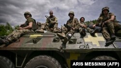 Ukrainian troops sit on an armored vehicle as they move back from the front line near the city of Slovyansk.