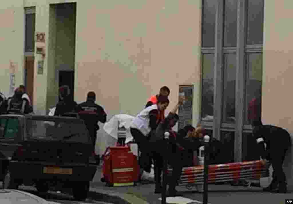 Firefighters and police officers gather in front of the offices of the French satirical newspaper Charlie Hebdo in Paris.