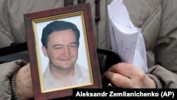 A portrait of whistle-blowing lawyer Sergei Magnitsky, who died in prison, is held by his mother, Natalia Magnitskaya, as she speaks during an interview.