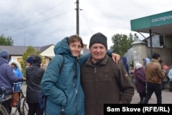 Nadia, who has been displaced twice in the past eight years, stands with a neighbor in Verbivka awaiting humanitarian aid.