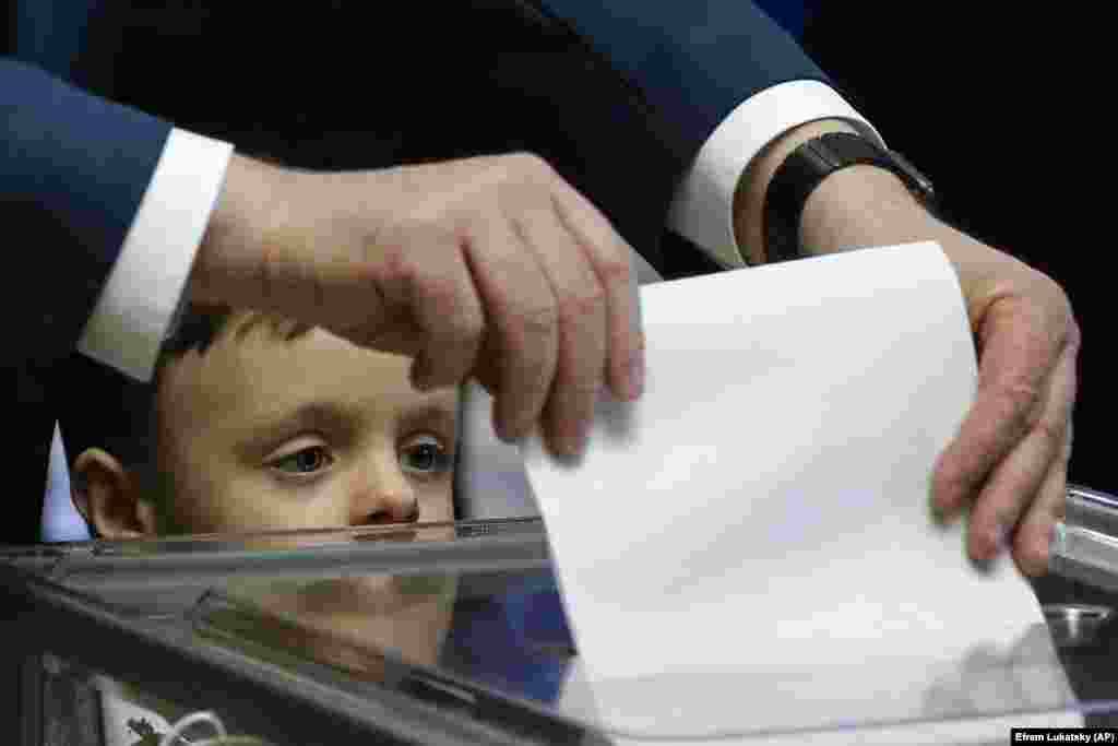 Ukrainian President Petro Poroshenko casts his ballot as his grandson, Petro, looks on, at a polling station in Kyiv. (AP/Efrem Lukatsky)