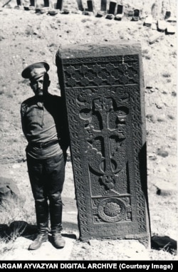 A soldier poses next to a Julfa khachkar in 1915.