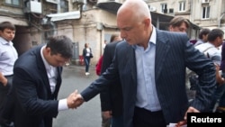 Oleksander Tymoshenko (right) shakes hands with an acquaintance in Kyiv in August.