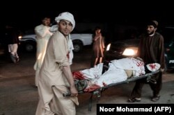 Men carry a wounded man outside a hospital following a car bombing outside a sports stadium in Lashkar Gah on March 23. Thirteen people were killed.