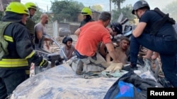 Rescuers release an injured man from a destroyed car at the site of an apartment building hit by a Russian missile strike in Dnipro on June 28.