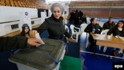 A woman casts her vote at a voting center in Pristina on December 1.