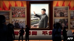 People stand in front of images of Chinese President Xi Jinping at the Museum of the Communist Party of China in Beijing in September 2022.