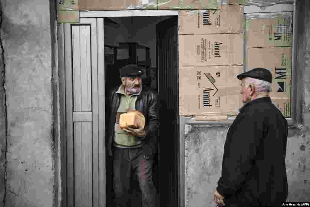 A man emerges from the bakery with fresh loaves of bread. &nbsp;