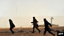 Libyan rebel fighters run to give assistance to their comrades after a Qaddafi air strike east of Ras Lanuf