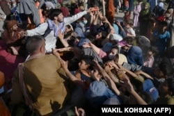 The situation was already desperate for some before the Taliban took Kabul. Internally displaced families who fled fighting between the Taliban and Afghan security forces receive food in Kabul on August 9.