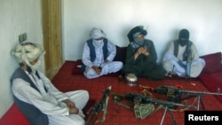 Taliban fighters pose with weapons as they sit in a room at an undisclosed location in southern Afghanistan in April 2011.