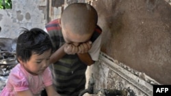 Children drinking water from a damaged building in Osh following the June violence.