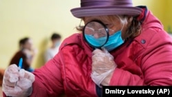 A woman uses a magnifying glass to fill out her ballot paper at a polling station in St. Petersburg.