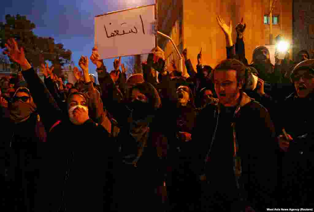 A woman holds a message to Iranian leaders with the word &quot;resign&quot; at a vigil for the victims of the air tragedy in Tehran on January 11.