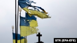 Damaged Ukrainian national flags flutter in the wind at a cemetery in Chernihiv in April.