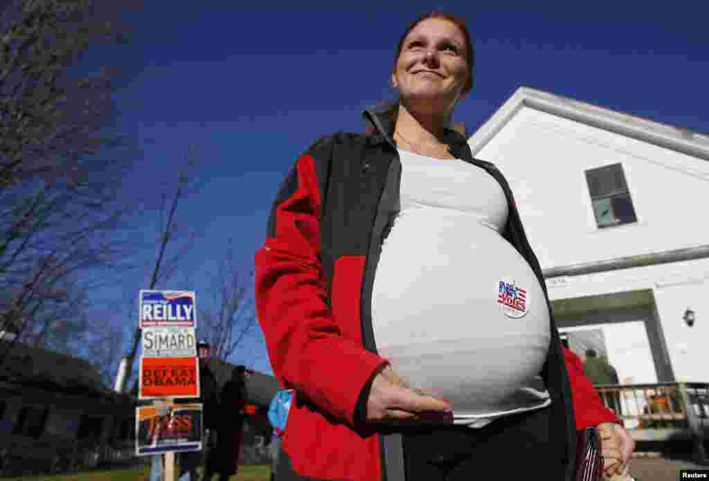 A pregnant woman shows off the voting sticker on her belly outside the old Town Hall in Bristol, New Hampshire.