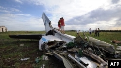 People pose while standing on the wreckage of a Ukrainian AN-26 military transport plane after it was shot down by a missile in the village of Davydo-Mykilske, east of Luhansk, near the Russian border on July 14.