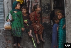 Afghan refugee children sit outside a shop on the outskirts of the eastern Pakistani city of Lahore.